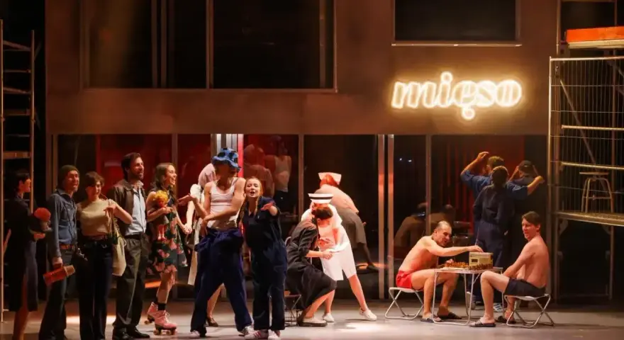 Scena z musicalu "1989". Aktorzy w strojach z epoki, neon "mięso" w tle.