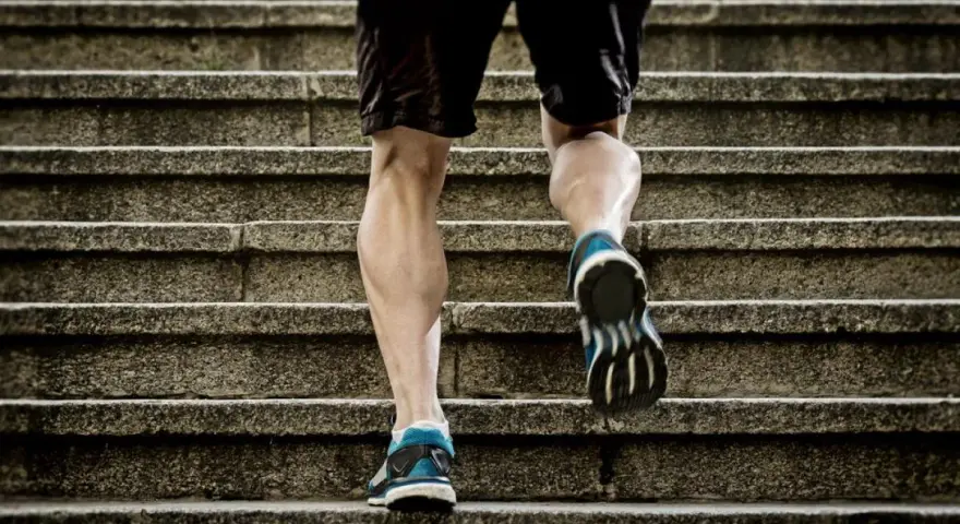 Un homme monte des escaliers, sollicitant ses mollets pour un excellent exercice.