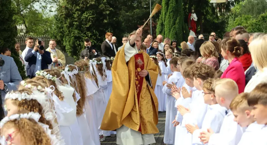 Uroczystość I Komunii Świętej. Dzieci w bieli, ksiądz błogosławi. Zastanawiasz się, ile kosztuje talerzyk na komunie?