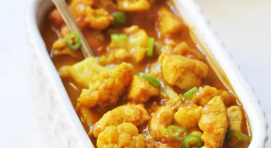 Aromatyczne curry z kurczakiem i kalafiorem w kremowym sosie, posypane zieloną papryczką chili.