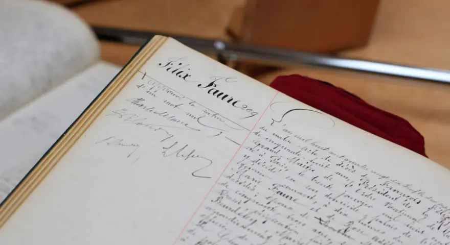 Comment consulter les registres d'état civil sur internet : un livre ancien manuscrit, peut-être un registre d'état civil, avec des écritures calligraphiées.