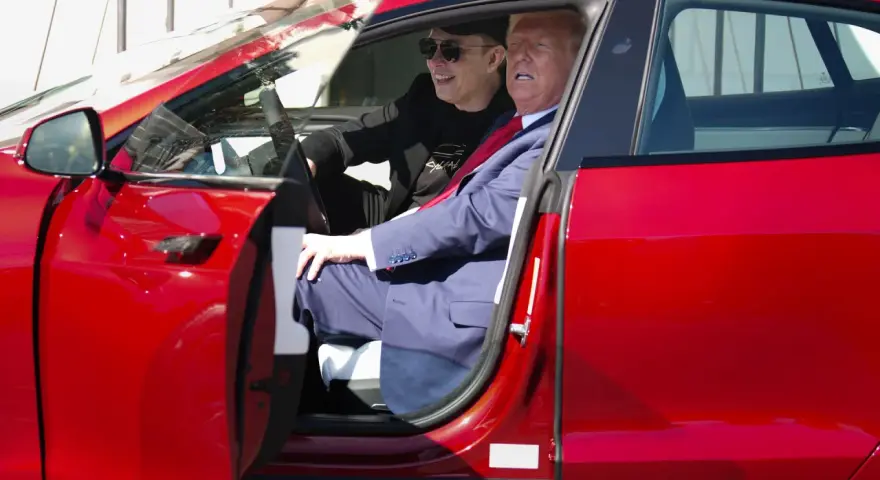 Elon Musk i Donald Trump siedzą w czerwonym samochodzie Tesla.