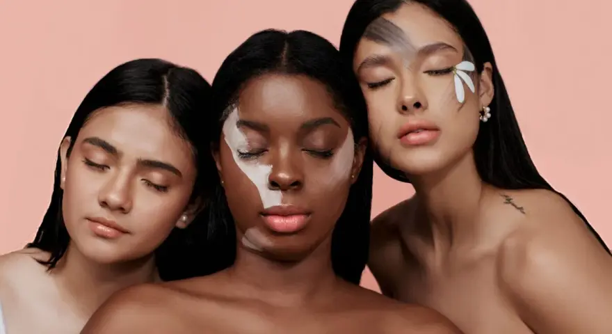 Tre donne con diverse tonalità di pelle, una con un trucco artistico sul viso, evocano la bellezza naturale e l'efficacia del palmitoyl tripeptide-1.