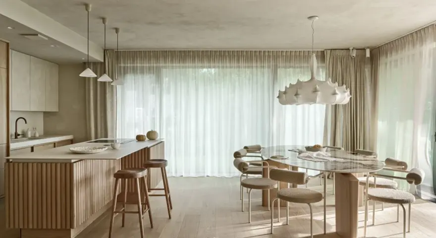 Nowoczesna kuchnia z wyspą i jadalnią. Wnętrze rozświetla designerska lampa wisząca, a całość dopełnia podwieszany sufit.