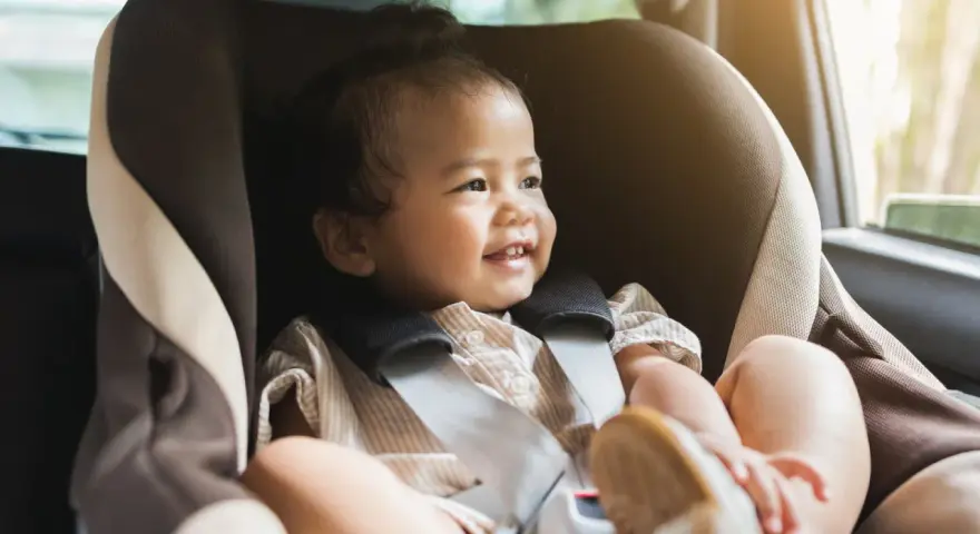 Glückliches Kleinkind im Kindersitz, bereit für eine Fahrt. Ein reboarder test zeigt, wie sicher es ist.