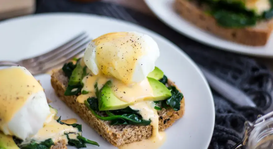 Pyszne jajka po florencku na tostach z awokado i szpinakiem, polane sosem holenderskim. Idealne na brunch!
