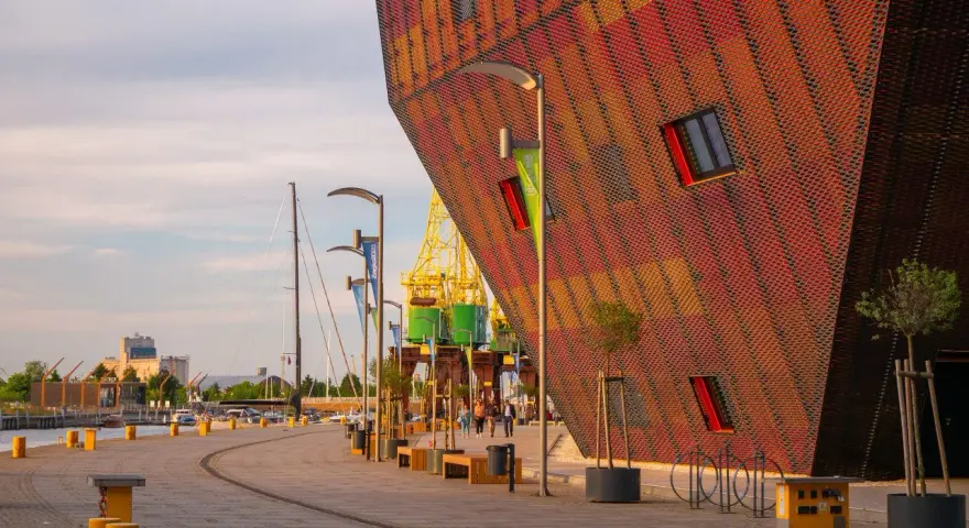Nowoczesna architektura i portowe klimaty – to właśnie co można zwiedzić w Szczecinie. Widok na nabrzeże z charakterystycznym budynkiem.