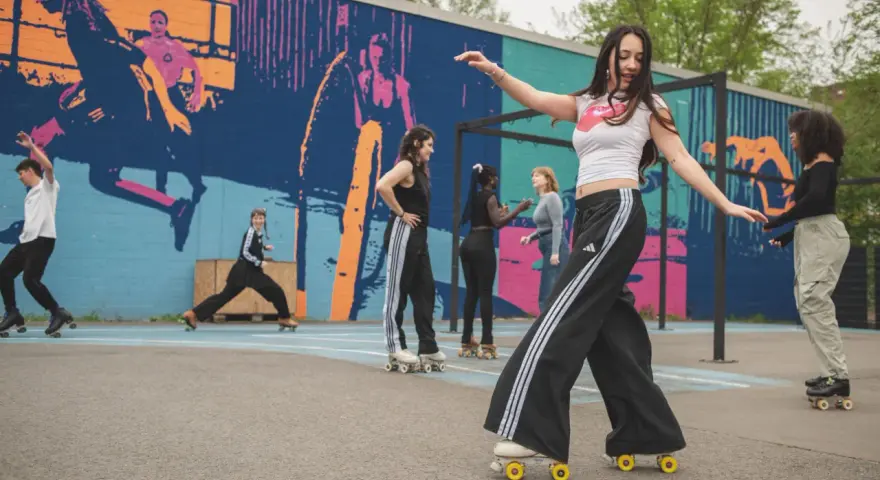 Eine Gruppe junger Leute genießt das Roller-Skating in Berlin vor einer bunten Wandmalerei.