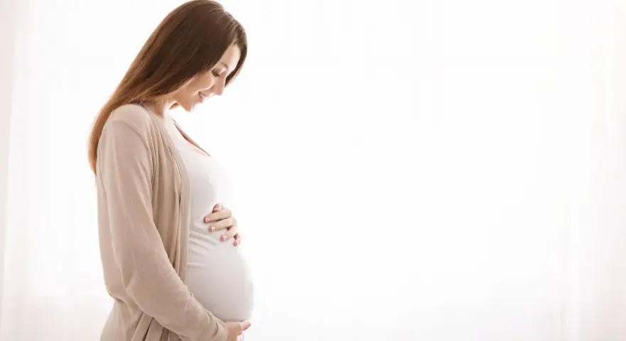 Kobieta w ciąży z hashimoto delikatnie dotyka brzucha, patrząc na niego z miłością.