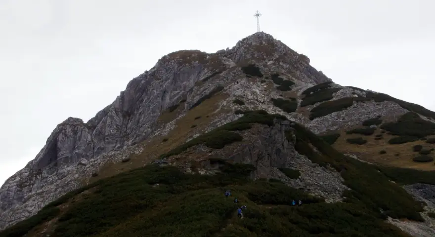 Wspinaczka na Giewont. Grupa turystów pokonuje skaliste zbocze, gdzie w trudniejszych miejscach pomagają łańcuchy.