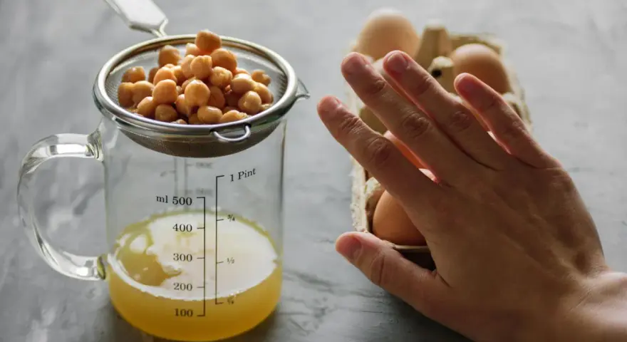 Kichererbsen im Sieb über Messbecher mit Aquafaba. Eier im Hintergrund. Perfekt für ei ersatz backen.