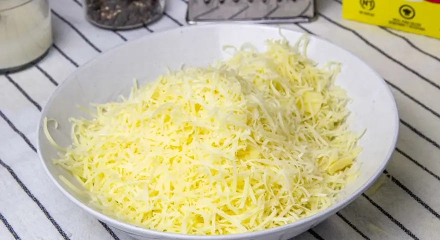 Queso rallado en un bol blanco, listo para hacer fondue.