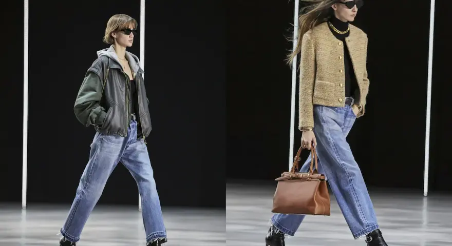 Due modelle sfilano con un **outfit jeans e stivali**. La prima indossa una giacca in pelle e cappuccio, la seconda un blazer beige.