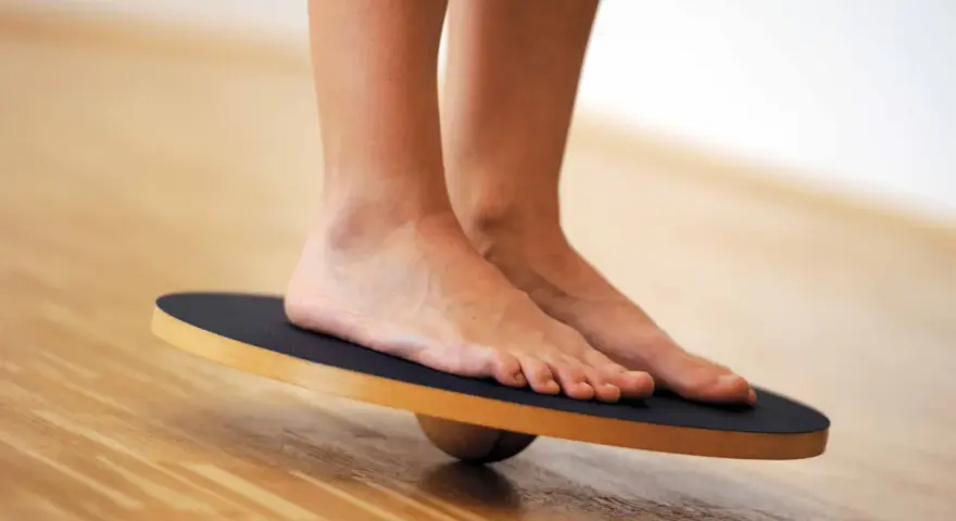 Piedi su una tavola di equilibrio, utili per esercizi di riabilitazione per distorsione caviglia.