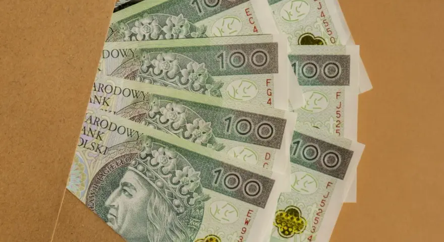 Stos banknotów 100 zł, idealnych na prezent, ile daje się na komunię?
