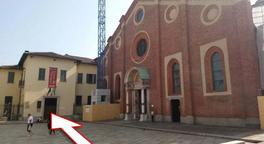 Plac przed kościołem z banerem "Cenacolo Vinciano". Bilety na Ostatnią Wieczerzę można kupić w pobliżu.