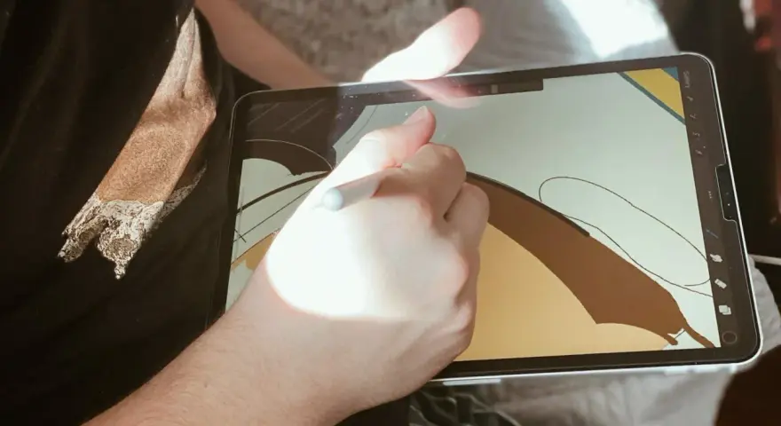 Osoba rysuje na ekranie iPad'a, używając rysika. To cyfrowy tablet graficzny, idealny do tworzenia sztuki.