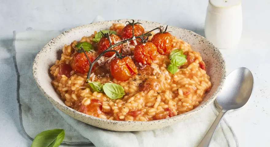 Cremiges Tomaten Risotto, garniert mit frischen Basilikumblättern und gerösteten Kirschtomaten. Ein Genuss für jeden Liebhaber italienischer Küche.