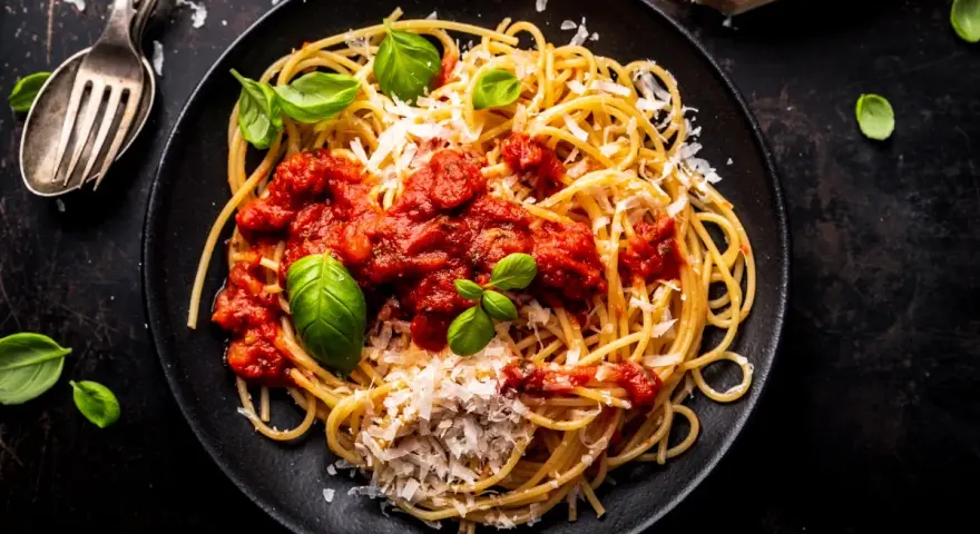 Talerz spaghetti z sosem pomidorowym, parmezanem i bazylią.