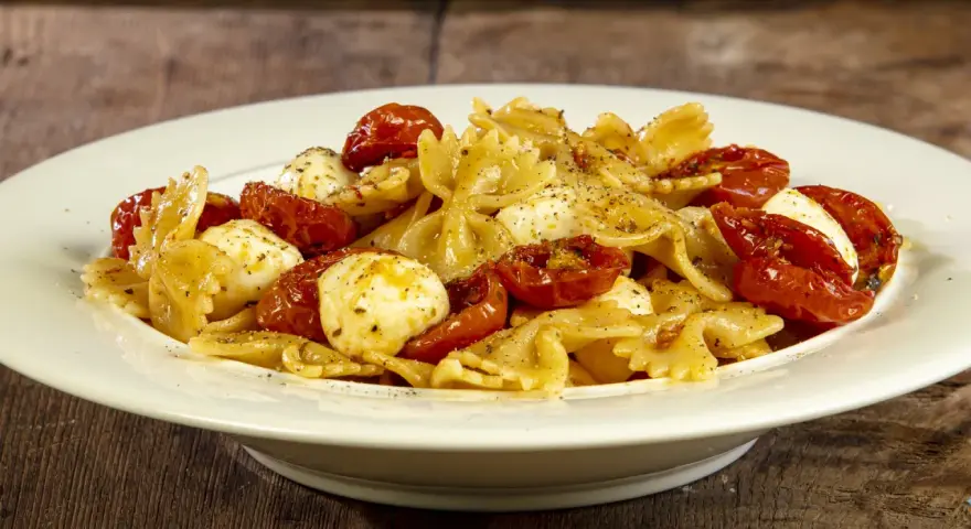 Farfalle con pomodorini confit, mozzarelline e un tocco di acciughe. Un piatto semplice e gustoso.