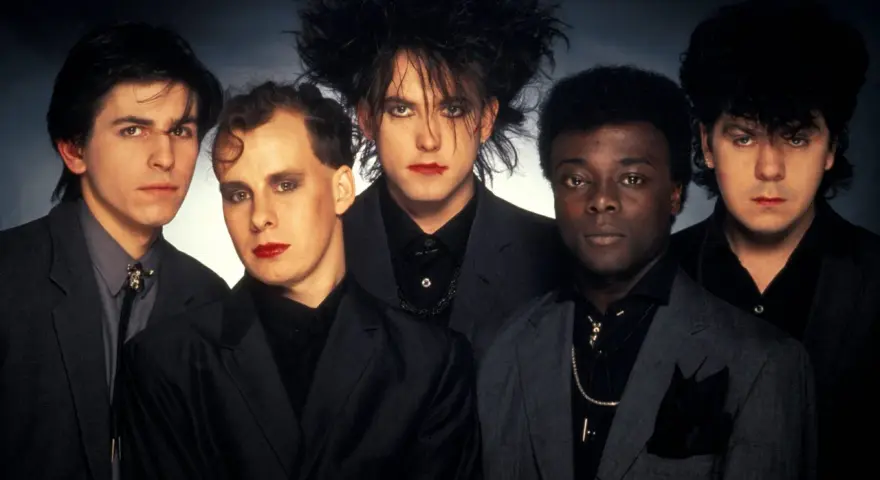 The Cure w pełnym składzie, z charakterystycznym makijażem i fryzurami, prezentują swoje kultowe utwory.