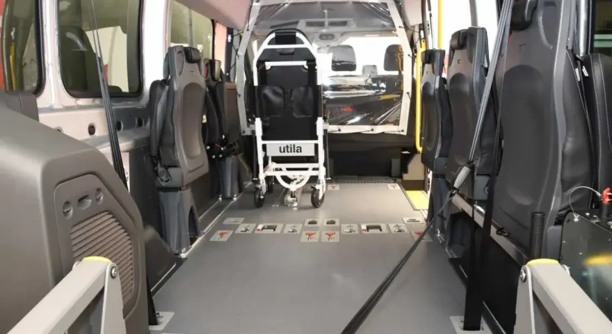 Innenraum eines Rollstuhlfahrzeugs, das als Taxi-Ersatz dient. Sitze und Rollstuhlhalterungen sind sichtbar.