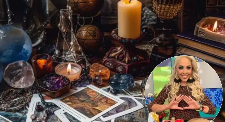 Mesa esotérica con cartas, cristales y velas. Una mujer sonríe haciendo un gesto con las manos, quizás buscando cómo atraer el amor.