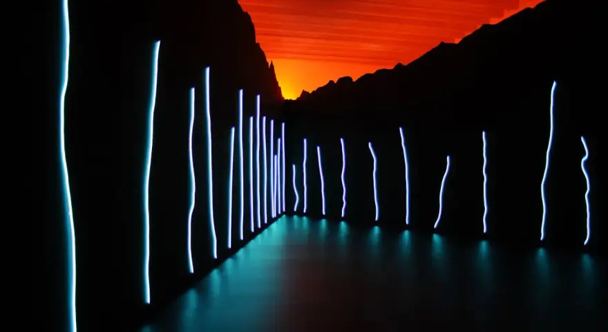 Installation lumineuse de Claude Lévêque, avec des néons bleus sur fond de ciel orangé et de montagnes sombres.