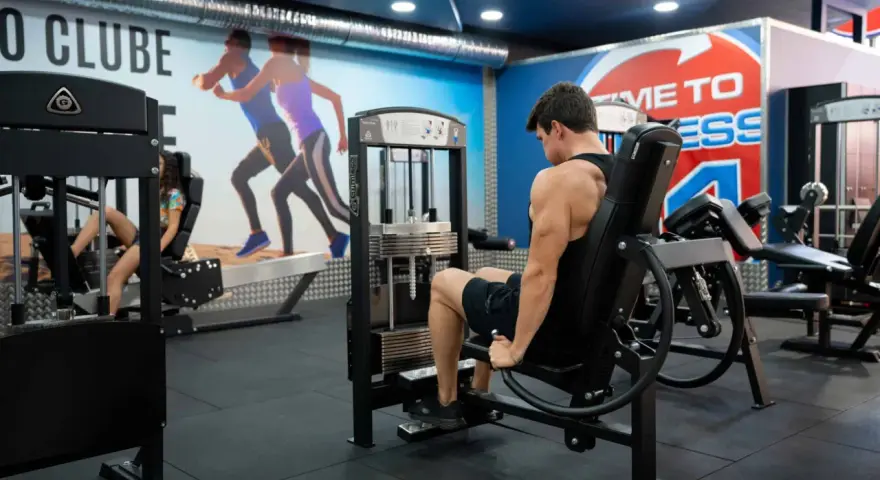 Man tränar ben på en **floor press**-maskin i ett modernt gym.