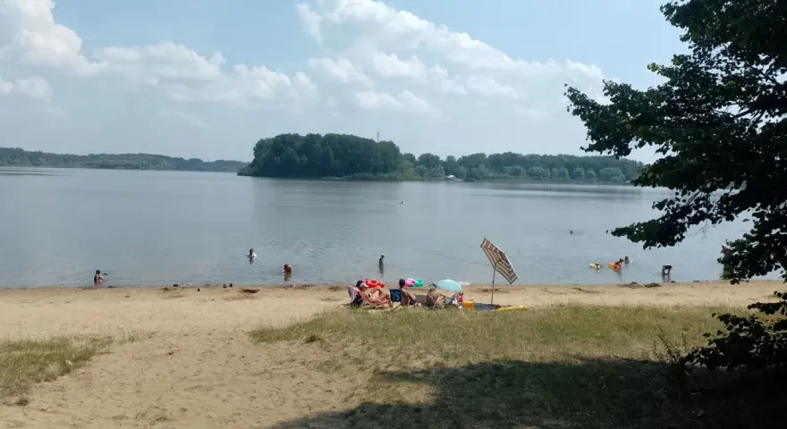 Na Jeziorze Przeczyckim można się kąpać. Ludzie odpoczywają na plaży i pływają w wodzie.