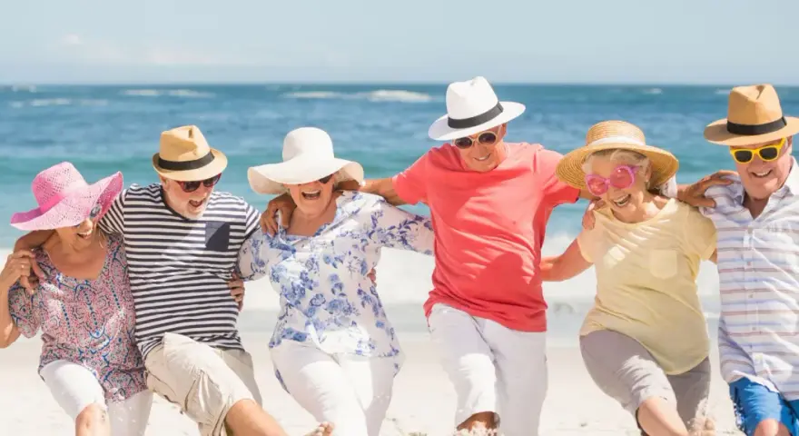 Szczęśliwi seniorzy na plaży, cieszący się słońcem i morzem. Idealne wczasy dla seniora 7 dniowe, pełne radości i wspólnych chwil.