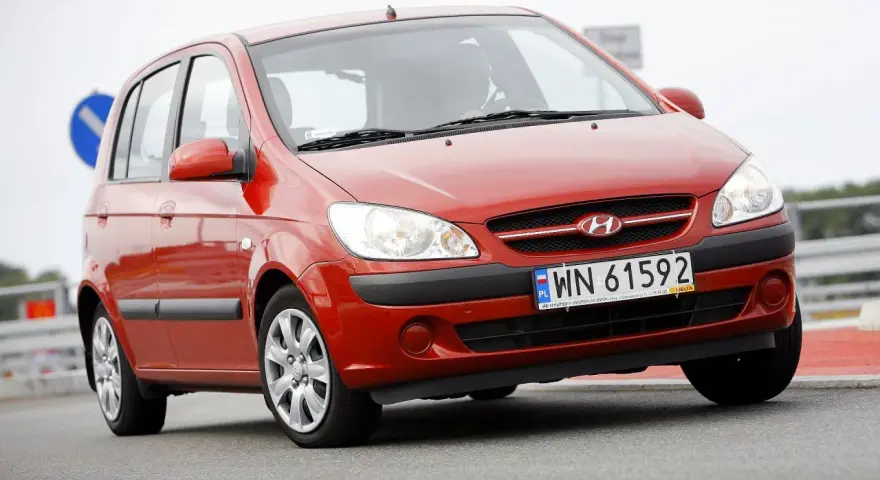 Czerwony Hyundai Getz na drodze. Kierowca za kierownicą, widoczna tablica rejestracyjna WN 61592.