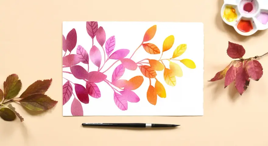 Aquarelle feuilles aux teintes roses, oranges et jaunes, évoquant l'automne. Une palette de couleurs et un pinceau sont disposés à côté.
