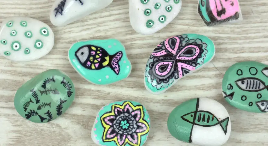 Ideas para pintar piedras de playa: peces, flores y diseños abstractos en tonos turquesa, blanco y rosa.