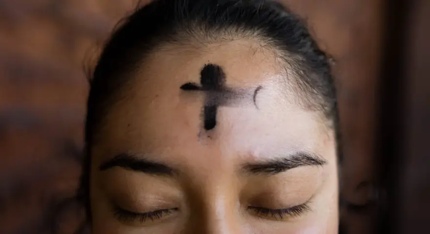 A cross of ashes marks a forehead, a solemn reminder of scripture for Ash Wednesday.