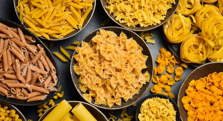 Różne rodzaje makaronu, od penne po farfalle, gotowe do przyrządzenia al dente. Idealne do każdej potrawy.