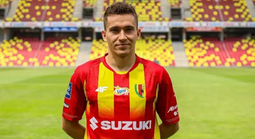 Piłkarz Korony Kielce w czerwono-żółtej koszulce na tle stadionu. Czekamy na kolejne transfery Korona Kielce!