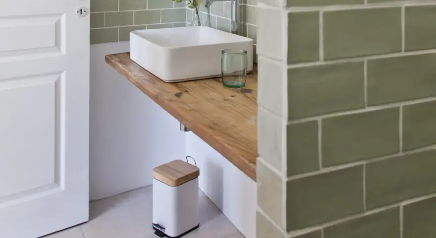 Plan de travail pour salle de bain avec lavabo carré, robinetterie moderne et poubelle design.