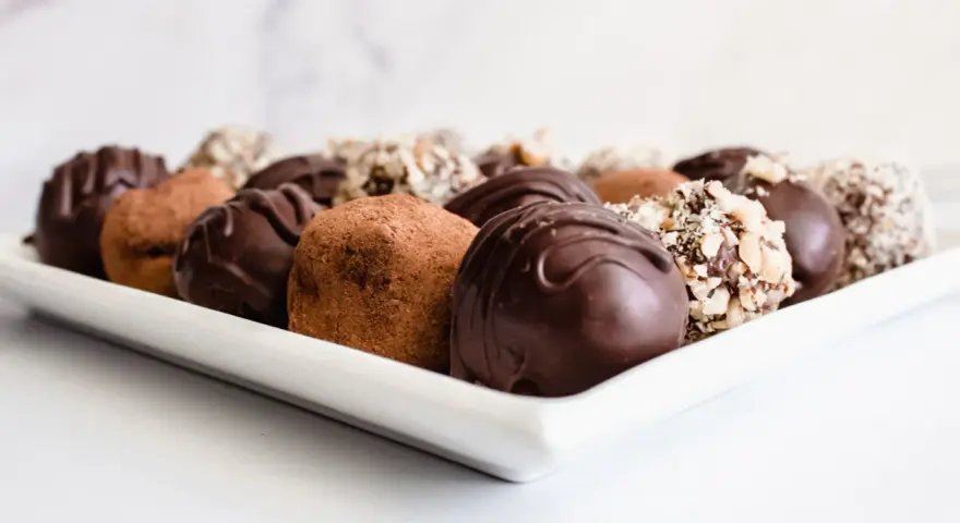 Variedad de trufas de chocolate, algunas cubiertas de cacao y otras con frutos secos picados. ¡Perfectas para aprender como hacer trufas de chocolate!