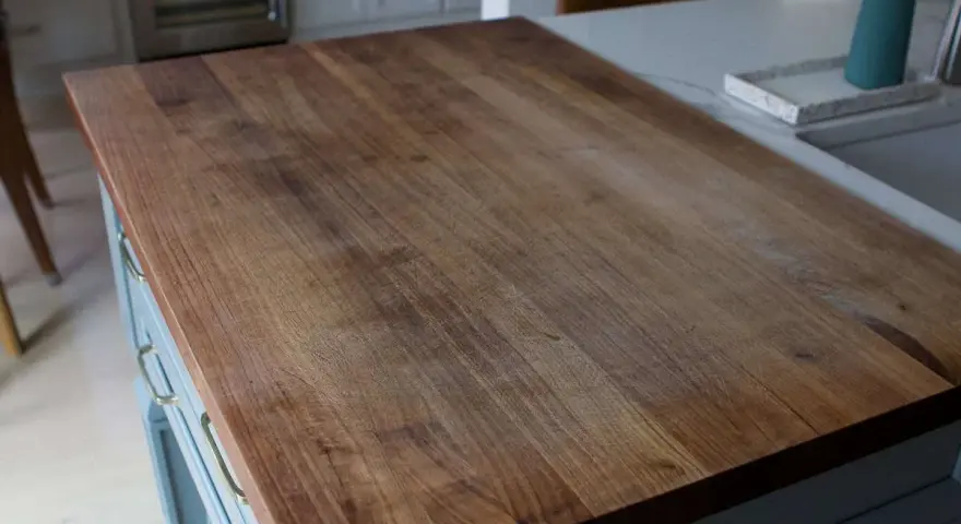 A close-up of a well-used butcher block countertop, showing the grain and minor scratches. This image illustrates how to clean butcher block countertops for a beautiful finish.
