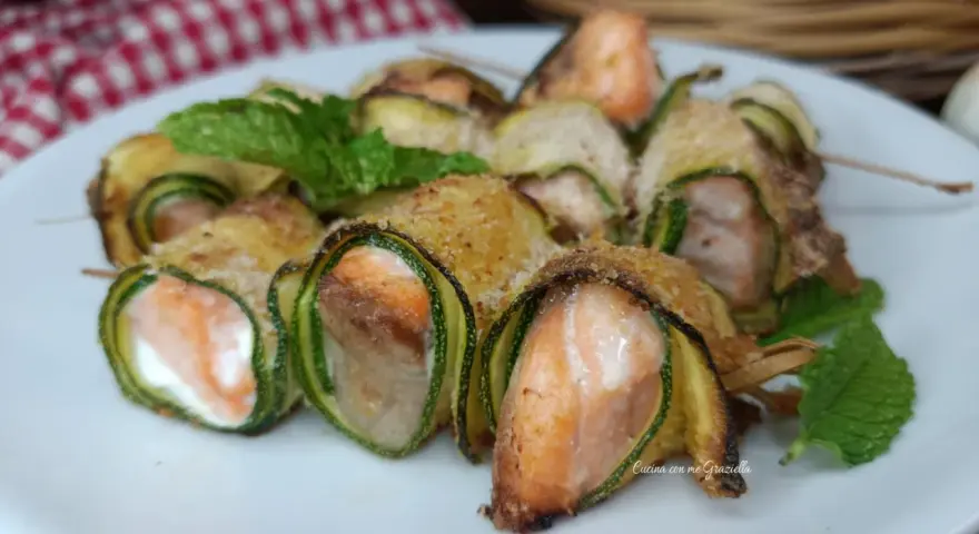Deliziosi involtini di zucchine con salmone e formaggio, guarniti con menta fresca.