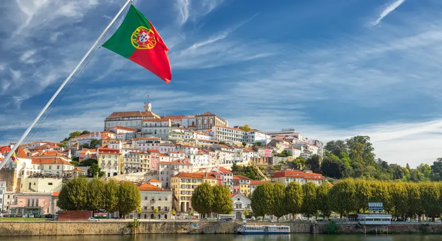 Wspaniała portugalia pogoda w grudniu. Flaga Portugalii powiewa nad malowniczym miastem na wzgórzu, z rzeką w tle.