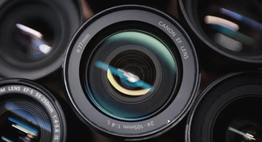 Zbliżenie na kilka obiektywów Canon, w tym teleobiektyw. Widać oznaczenia "CANON EF LENS", "24-105mm 1:4 L" i "EF-S 55-250mm".