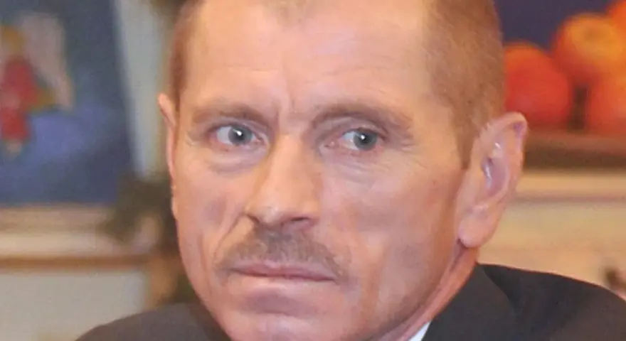 Portret Stanisława Pąka. Mężczyzna z wąsikiem patrzy w bok. W tle owoce.