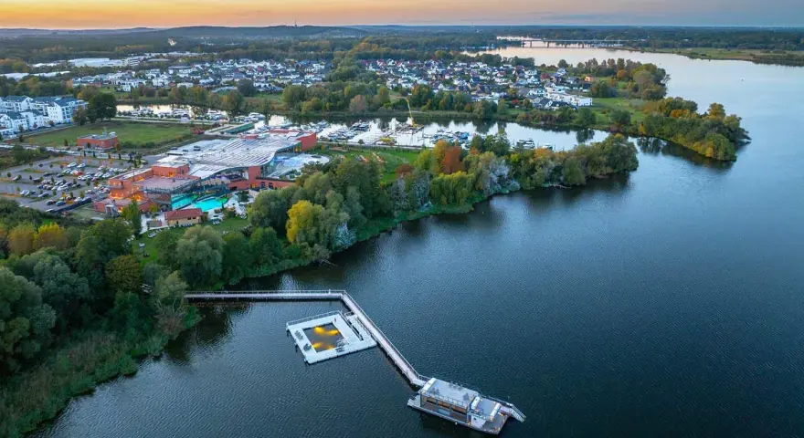 Luftaufnahme der Havel Therme mit einem schwimmenden Pool auf dem Wasser. Ein idyllisches Bild der Entspannung am See.