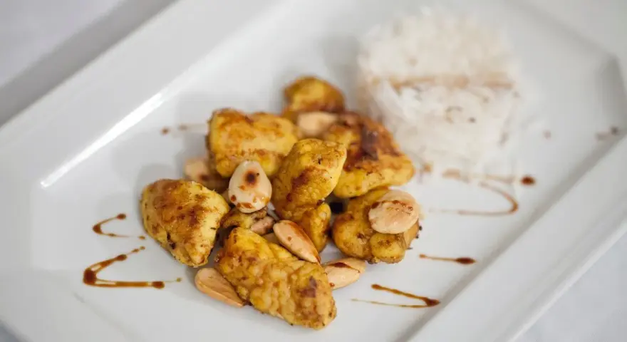 Piatto di cous cous con pollo al curry, mandorle e riso bianco.