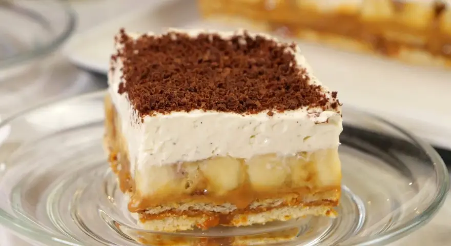 Przepis na Banoffee Pie: warstwy ciastek, karmelu, bananów i bitej śmietany, posypane czekoladą.