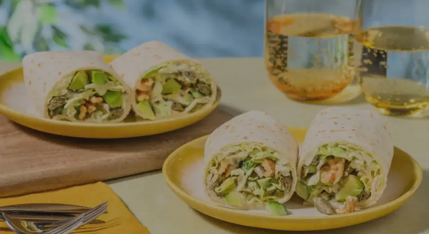 Leckeres Tortilla-Rezept mit Avocado und Garnelen, serviert auf gelben Tellern mit Gläsern mit Getränken.