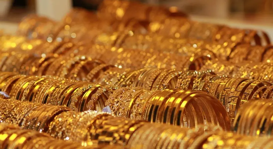 Una ricca collezione di bracciali d'oro, molti con il marchio 750, brillano sotto la luce, creando un'abbagliante esposizione di lusso.