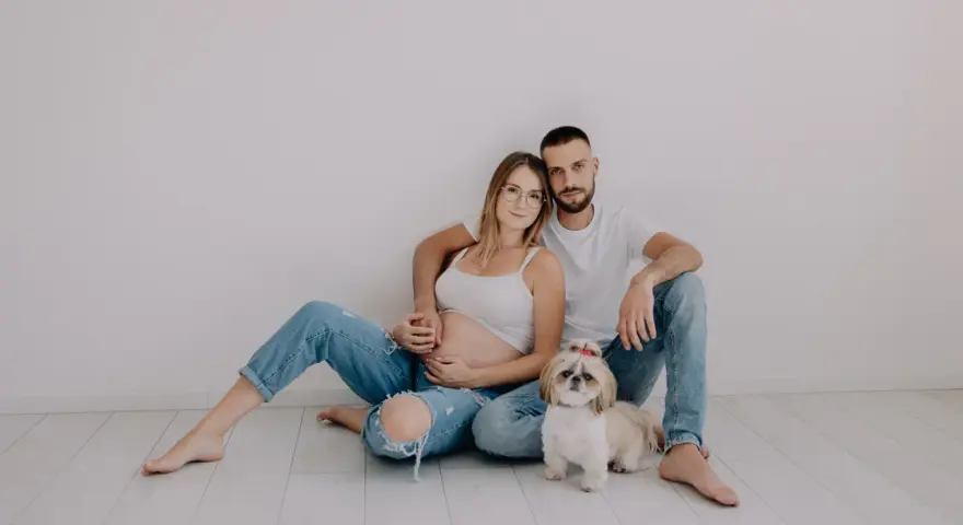 Ciąża w obiektywie laura kania fotografia: przyszli rodzice z pieskiem siedzą na podłodze.